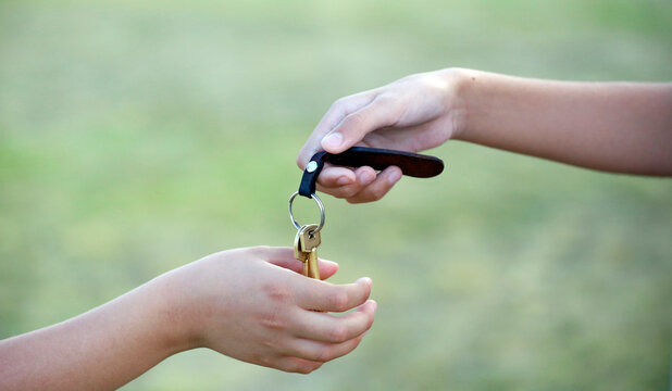 Keys delivery. Two people exchanging keys to a house. Children handing each other keys with key ring. Isolated. House keys. Household keys. Living place. Concept. Real estate sale conceptual image.
