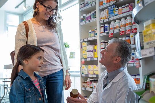 Pharmacist consulting mother and daughter in market