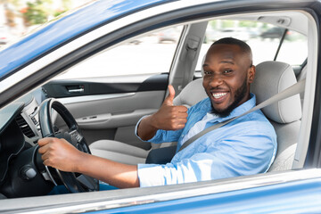 Happy black man sitting in car gesturing thumbs up