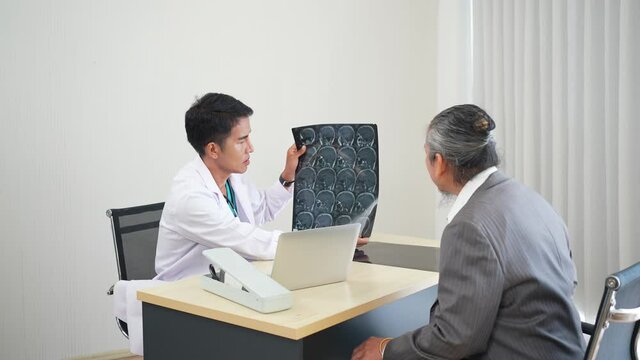 asian doctor interpret mri brain result to senior patient who visit at hospital clinic