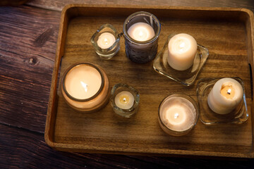 Interior and home cosiness concept. Top view. Lighted candles of various sizes and shapes in glass...