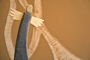 wooden painted angel on abstract blurry background, old handicraft figurines, background with winding motif with free space for text, beautiful angels in folk minimal style for wallpaper 