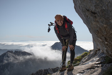 chica en la montaña con una mochila y mar de nubes de fondo