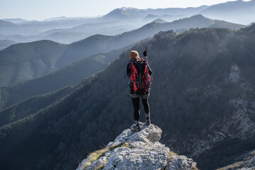 chica en la montaña con una mochila y mar de nubes de fondo