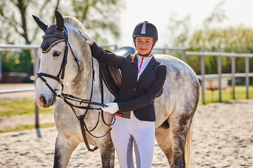 Beautiful horse rider girl stands near a horse on a farm 