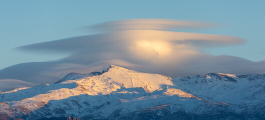 Spectacular lenticular clouds over the peaks of Sierra Nevada (Spain) at sunset in winter