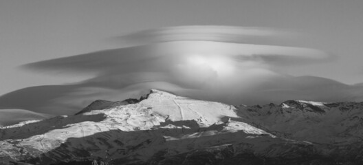 Spectacular lenticular clouds over the peaks of Sierra Nevada (Spain) at sunset in winter