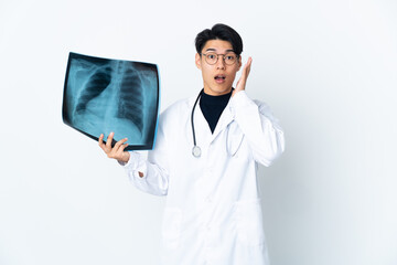 Young Chinese doctor man holding radiography isolated on white background with surprise and shocked...