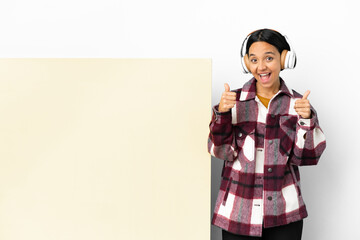 Young woman listening music with a big empty placard over isolated background giving a thumbs up gesture