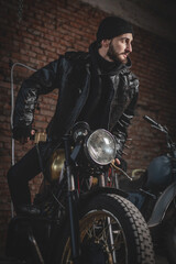 Fototapeta na wymiar Motorbiker in the black leather jacket near the the old motorbike concept.