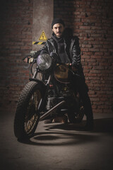 Obraz na płótnie Canvas Motorbiker in the black leather jacket near the the old motorbike concept.