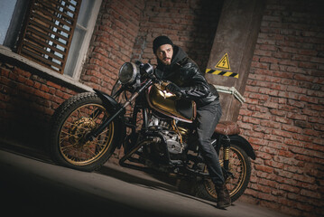 Fototapeta na wymiar Motorbiker in the black leather jacket near the the old motorbike concept.