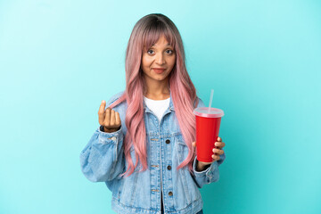 Young mixed race woman drinking a fresh drink isolated on blue background making money gesture