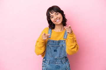 Young woman with overalls isolated background pointing front with happy expression