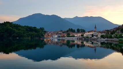 Fototapeta na wymiar Picturesque little lakeside village Mergozzo at sunset, beautiful reflection in the water. Piedmont, Northern Italy.