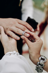 Close-up of how a girl puts a wedding ring in boho style on her husband's finger
