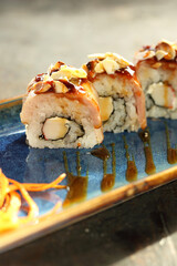 Sushi with salmon and roasted almonds.
Traditional sushi rolls on a blue plate.