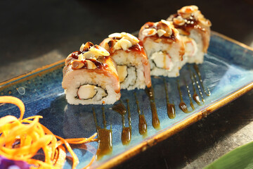 Sushi with salmon and roasted almonds.
Traditional sushi rolls on a blue plate.