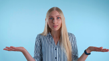 Fototapeta premium Blonde young woman misunderstanding something on blue background. She showing this emotion on face and in gesture.