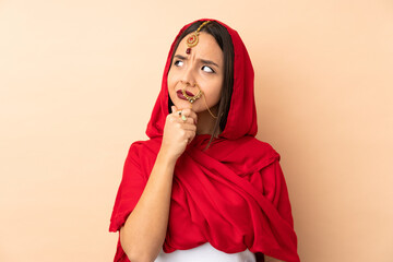 Young Indian woman isolated on beige background having doubts