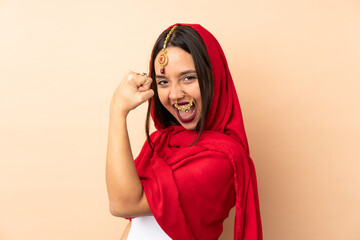 Young Indian woman isolated on beige background doing strong gesture