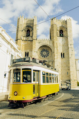 Fototapeta na wymiar Yellow tram next to the cathedral of Lisbon, Portugal