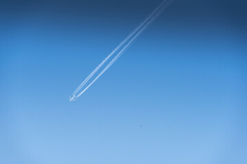 Passenger plane and contrails in blue sky