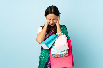 Young Indian woman with shopping bags frustrated and covering ears