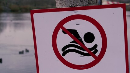 Prohibition sign. The sign prohibits swimming in the pond.