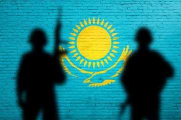 Kazakhstan flag painted on a brick wall with soldiers shadows. War concept