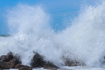 Spuma marina di una grande onda che si rompe sugli scogli.