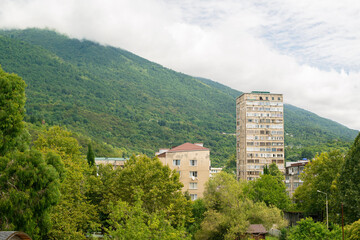 Fototapeta premium an old multi-storey house on the background of a green mountain in summer