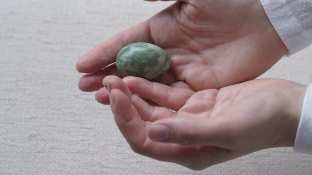 Woman's hands holding and showing a jade egg, slow motion