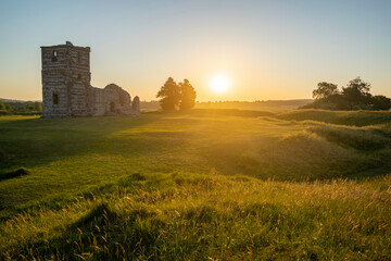Fototapeta premium Sunrise over the old ruins of Knowlton Church And Earthworks with sun illuminating the surrounding landscape. Knowlton, Wimborne, Dorset, England