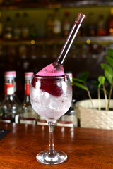 Red fruit drink served in an exotic glass with dehydrated fruit and ice