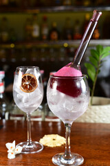 Red fruit drink served in an exotic glass with dehydrated fruit and ice