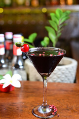 black red fruit drink served in an exotic glass with dehydrated fruits, negrone and ice