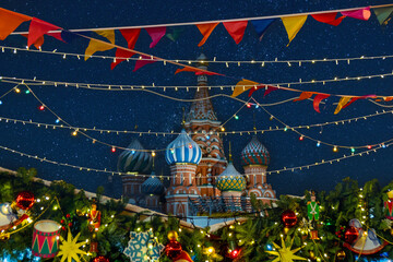 Night view to the Saint Basil's Cathedral located at Red Square Moscow, decorated for Christmas and New Year celebration. Colorful flags and toys hang over pine trees. 