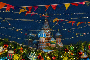 Night view to the Saint Basil's Cathedral located at Red Square Moscow, decorated for Christmas and New Year celebration. Colorful flags and toys hang over pine trees.