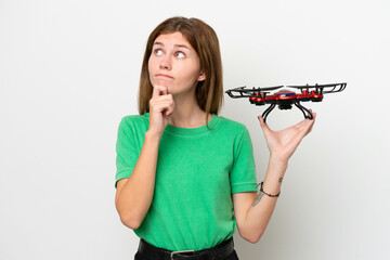 Young English woman holding a drone isolated on white background having doubts and thinking