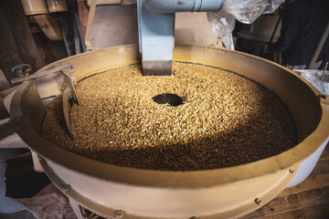 Bowl of wheat at rotating mill stone used to crush wheat to produce flour