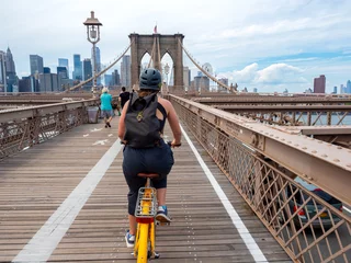 Photo sur Aluminium Brooklyn Bridge Woman riding a yellow bike across the Brooklyn Bridge with a view from behind