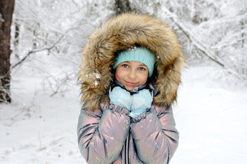 Obraz premium A girl in warm winter overalls on a walk in the winter forest: active games, playing snowballs and other activities