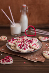 valentine's day. cookies in the shape of hearts. valentine's day pastries on a dark wooden background. shortbread cookies with a glass of milk on a dark wooden background.