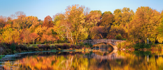 autumn landscape with lake, bridge, and trees.