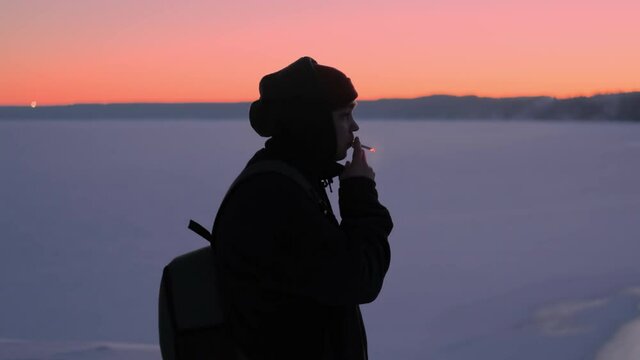 Winter. A lonely teenager smokes a cigarette and admires the sunset. Night time