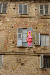 Dettaglio di palazzo antico con vestiti appesi ad una persiana aperta (Umbria, Perugia, Italia)