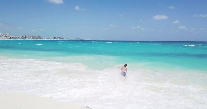 aerial view of a young man running and jumping into the Caribbean Sea, Playa del Carmen, Cancun, Mexico