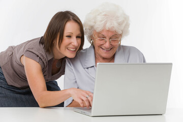Junge Frau hilft Seniorin bei der Arbeit am Computer