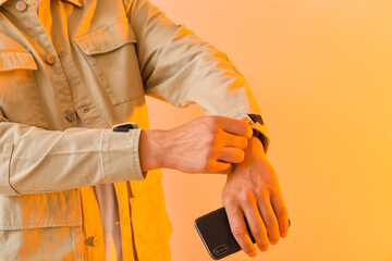 Young man in stylish jacket with mobile phone on light background, closeup